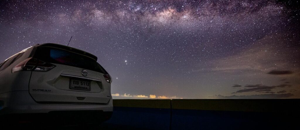 Vehicle receiving enhanced 24/7 roadside assistance at night under a starlit sky, provided by Gonzalez MotorSport.